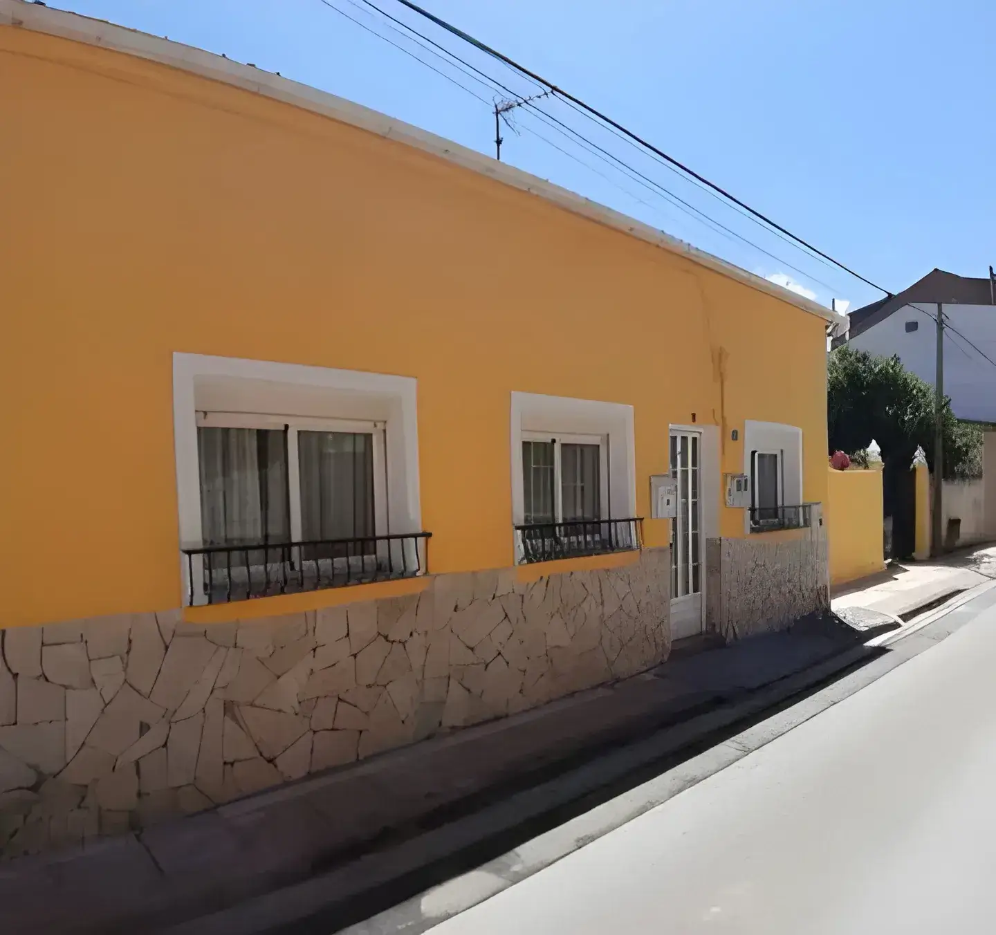 El Pintor en Cádiz Fachada de casa tradicional pintada en color amarillo con zócalo de piedra